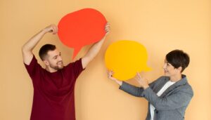 Two people holding speech bubbles representing language learning and communication