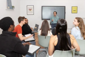 Spanish teacher leading a dynamic group class at LAE Madrid with engaged international students in a bright, modern classroom