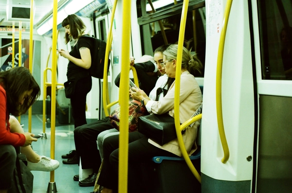 Pasajeros sentados y de pie en el metro de Madrid, utilizando sus móviles durante el trayecto.