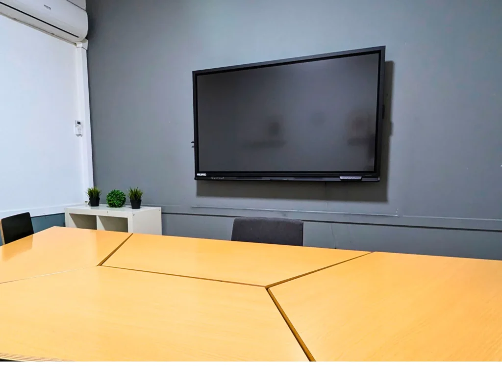 Modern Spanish classroom at LAE Madrid with digital whiteboard, triangular tables, and minimalist setup