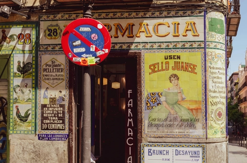 Fachada de una antigua farmacia tradicional en Madrid con azulejos decorativos y carteles vintage.
