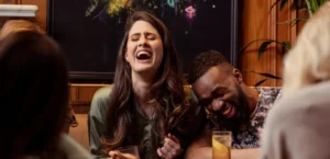 A diverse group of friends laughing and enjoying drinks at a traditional Madrid bar, illustrating social integration through Spanish language skills.