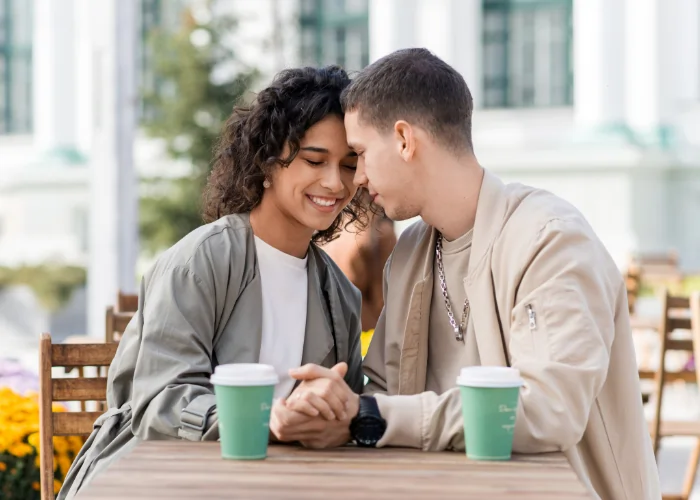 A man sharing a joke with a laughing woman, illustrating the social connection and warm communication skills gained while learning Spanish in Madrid