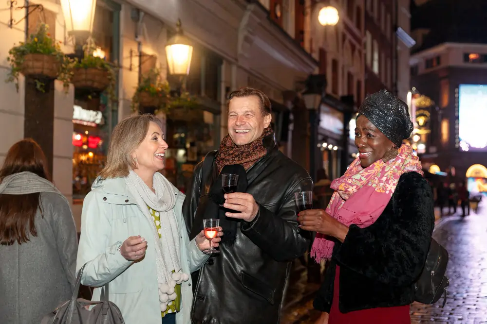 A diverse group of friends laughing and enjoying drinks on a brightly lit Madrid street at night, illustrating the late-night social culture and evening energy.