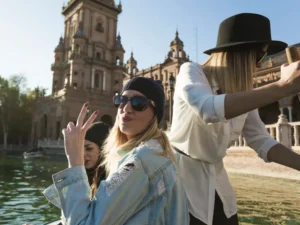 A group of young women enjoying a sunny afternoon by the water in a historic Spanish plaza, capturing the vibrant "Rhythm of Life" and outdoor social energy of Madrid in spring.