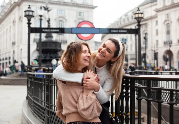 Dos amigas riendo en una plaza de Madrid, representando la integración social y el sentimiento de hogar.