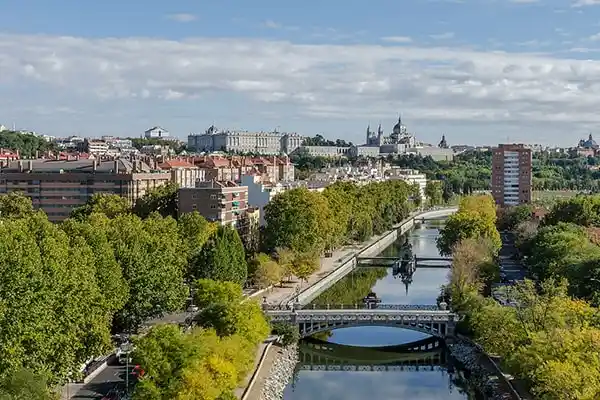 Vista primaveral del lago en la Casa de Campo de Madrid con personas paseando y disfrutando al aire libre