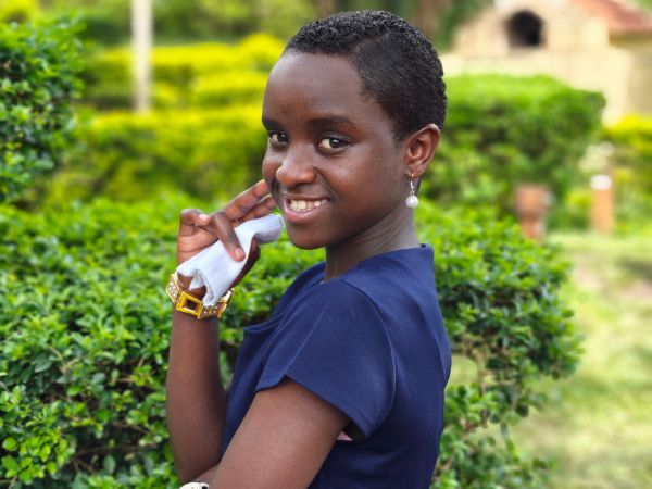 Smiling student in navy blue dress supported by LAE Madrid and Kelele África sponsorship program
