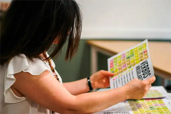 Spanish teacher at LAE Madrid reviewing a colorful irregular verb chart during a grammar lesson