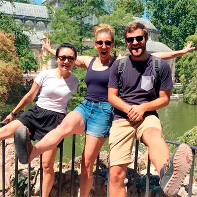 Three international LAE Madrid students enjoying a sunny day at Retiro Park in Madrid, smiling and posing playfully
