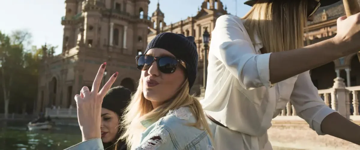 A group of young women enjoying a sunny afternoon by the water in a historic Spanish plaza, capturing the vibrant "Rhythm of Life" and outdoor social energy of Madrid in spring.