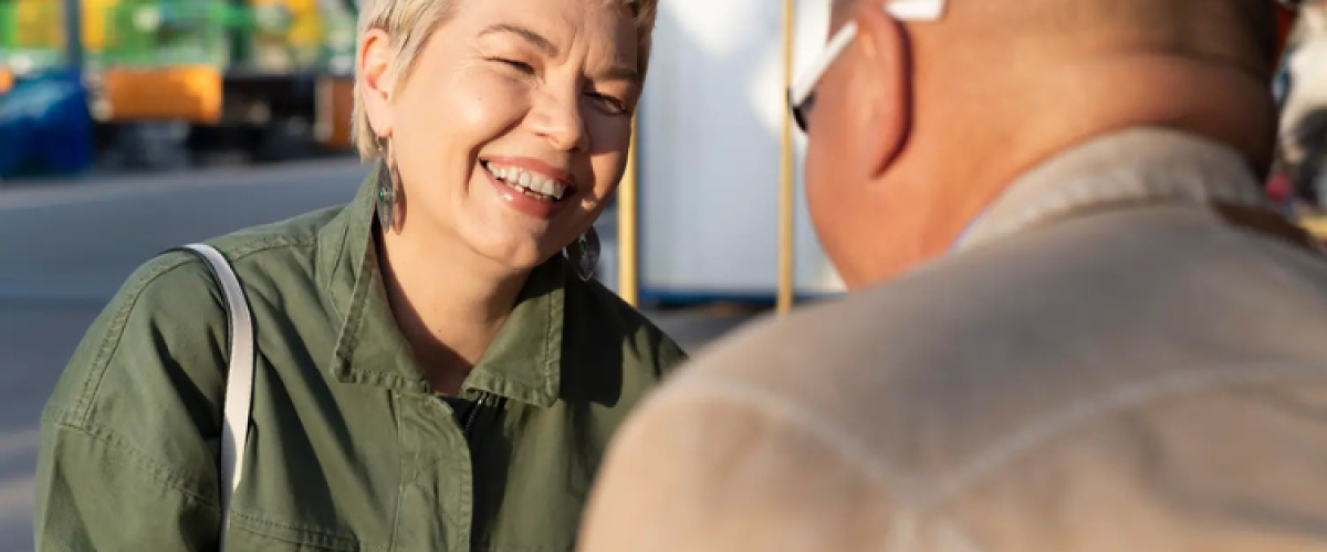 Una pareja de mediana edad sentada a la mesa en un ambiente cálido y acogedor, sonriendo y manteniendo una conversación auténtica y relajada.